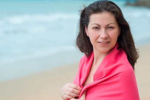 portrait of a brunette woman wrapped in a towel at the beach