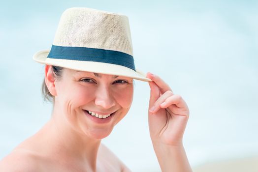 portrait of a happy woman on the beach wearing a straw hat