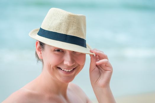 woman in a straw hat smiling, portrait on the beach close-up