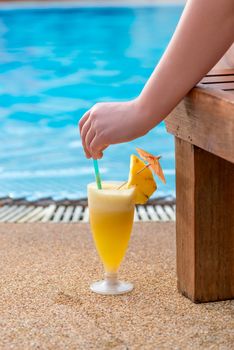 cocktail, woman's hand and view of the pool in the tropics