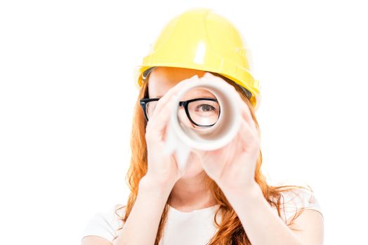Portrait of a woman builder who looks through blueprints as in a telescope on a white background