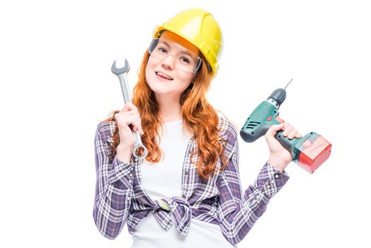 horizontal portrait of a woman with red hair with tools in a yellow hard hat isolated