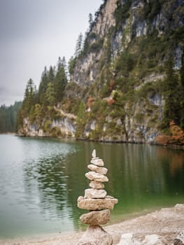 Stack of stones placed on shore of lake in mountains.