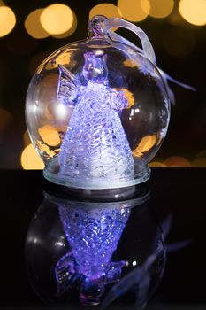 Illuminated angel figure in glass bulb, soft boke christmas lights as background, Christmas decoration