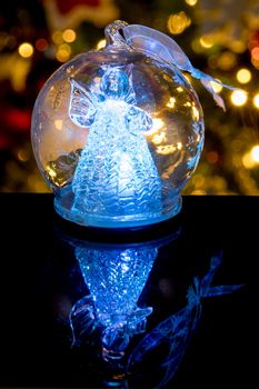 Illuminated angel figure in glass bulb, soft boke christmas lights as background, Christmas decoration