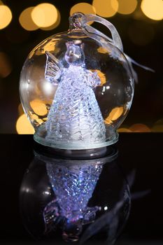 Illuminated angel figure in glass bulb, soft boke christmas lights as background, Christmas decoration