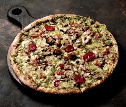 Delicious Homemade Pizza with Bacon, Cheese, Roasted Bell Pepper, Zucchini and Alfredo Sauce on Wooden Cutting Board closeup on Grange Dark background