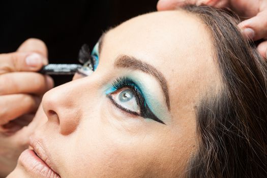 Makeup artist applying blue eyeshadow on white woman eyes