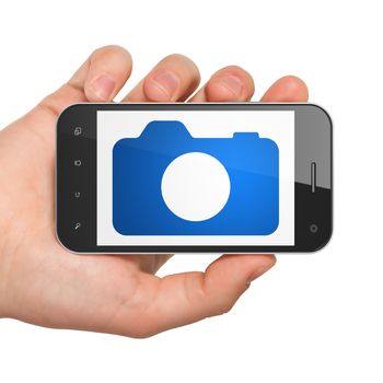 Travel concept: Hand Holding Smartphone with  blue Photo Camera icon on display,  Tag Cloud background, 3D rendering
