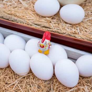 White chicken eggs leaning on straw in wooden basket,close up.