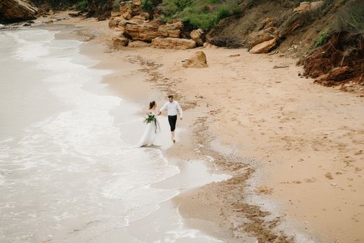 young couple groom with the bride on a sandy beach at a wedding walk