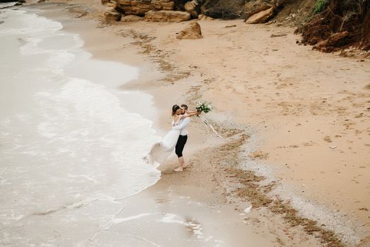 young couple groom with the bride on a sandy beach at a wedding walk