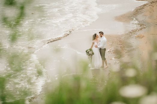 young couple groom with the bride on a sandy beach at a wedding walk