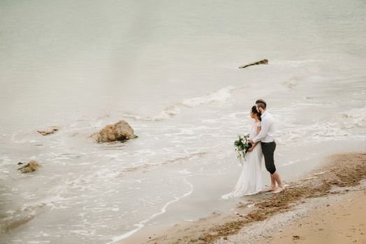 young couple groom with the bride on a sandy beach at a wedding walk