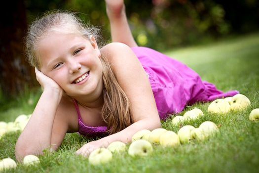 Nice young girl with stack of green fresh apples in the garden
