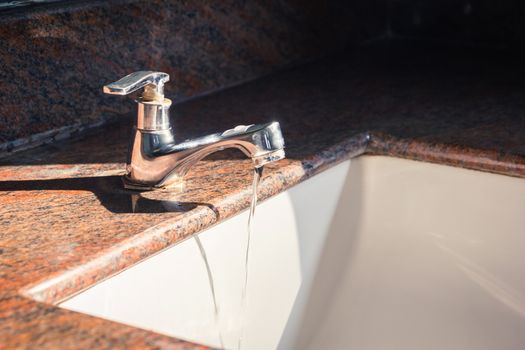 Close up of faucet and water flow on basin