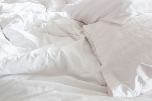 top view of white pillow on bed and with wrinkle messy blanket in bedroom, from sleeping in a long night.