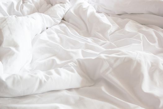 wrinkle messy blanket and white pillow in bedroom after waking up in the morning, from sleeping in a long night, details of duvet and blanket, an unmade bed in hotel bedroom with white blanket.