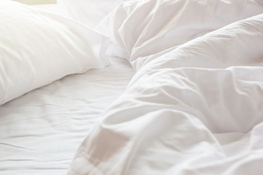 wrinkle messy blanket and white pillow in bedroom after waking up in the morning, from sleeping in a long night, details of duvet and blanket, an unmade bed in hotel bedroom with white blanket.