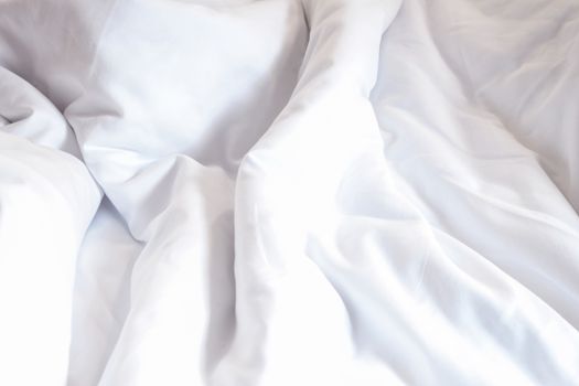 white pillow on bed and with wrinkle messy blanket in bedroom, from sleeping in a long night.