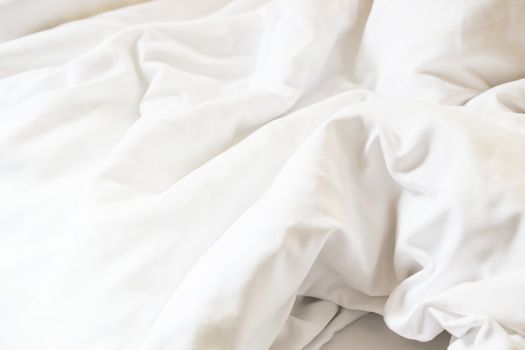 white pillow on bed and with wrinkle messy blanket in bedroom, from sleeping in a long night.