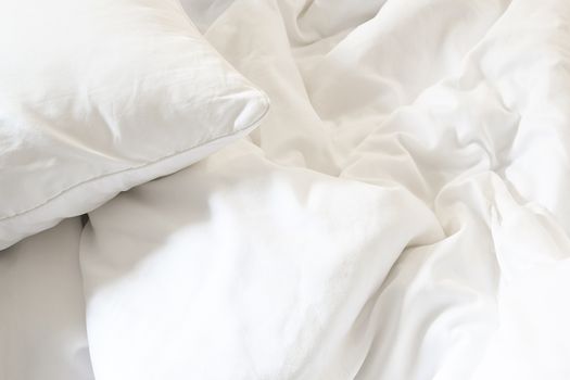 white pillow on bed and with wrinkle messy blanket in bedroom, from sleeping in a long night.