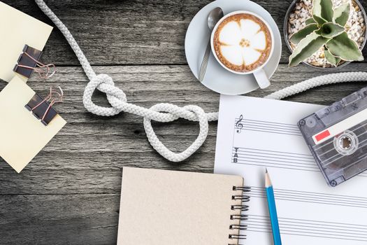 Sheet music, cactus, fountain pen, tape cassette and coffee latte on vintage wooden table