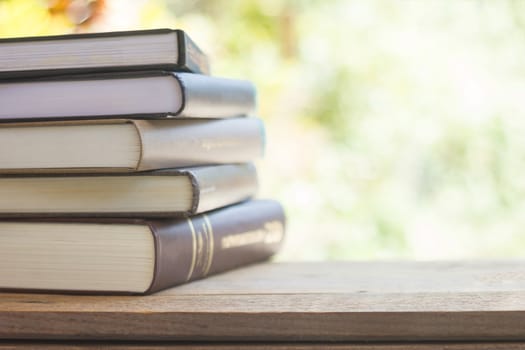 stack of thick books with green light and bokeh background