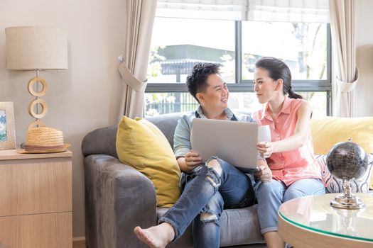 Young Couples using laptop tohether in living room of contemporary house for modern lifestyle concept