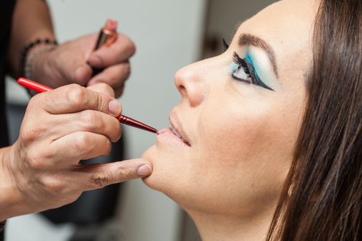 Makeup artist applying lipstick to a white woman