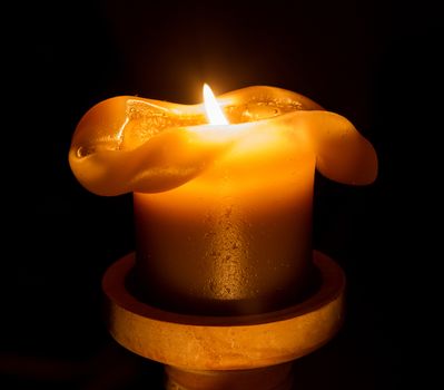 Large candle burning in the darkness, selective focus