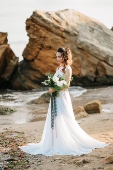 bride with a wedding bouquet on the shore of the black sea in the sunset light