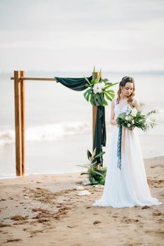 bride with a wedding bouquet on the shore of the black sea in the sunset light