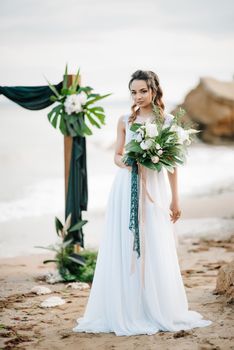 bride with a wedding bouquet on the shore of the black sea in the sunset light