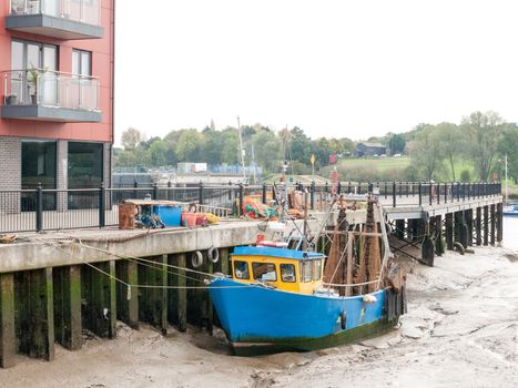 blue fishing boat parked in pier mud dock; essex; england; uk