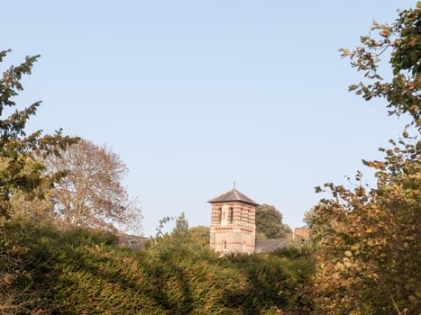 old stone tower in distance in sky behind hedge tree tops; essex; england; uk