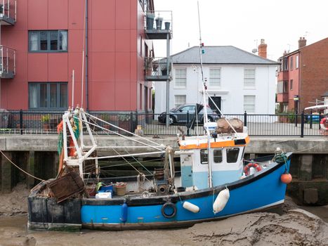 blue fishing boat parked in pier mud dock from side view; essex; england; uk