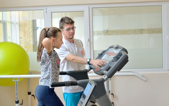 Instructor in gym with little girl on treadmill