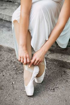 Legs of a beautiful ballerina close-up. Pointe shoes on concrete stairs