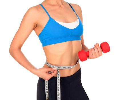 Closeup shot of slim young woman holding red dumbbell and measuring her thin waist with a tape measure, isolated on white background