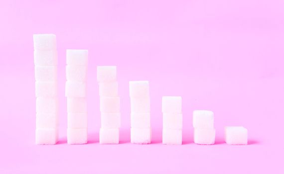 High to low stacks of sugar cubes with pink background, health care diet concept