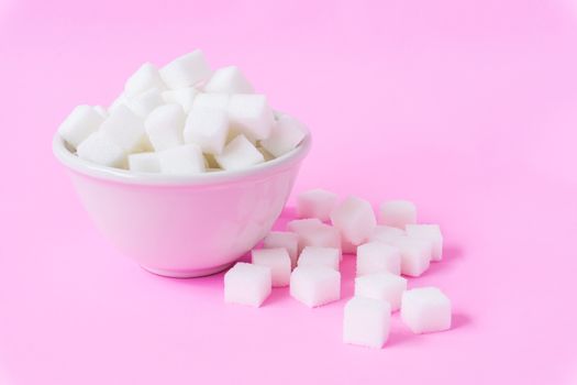 Closeup sugar cubes on bowl with pink background, health care concept