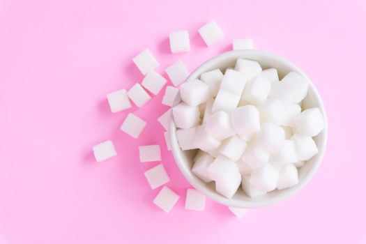 Closeup sugar cubes on bowl with pink background