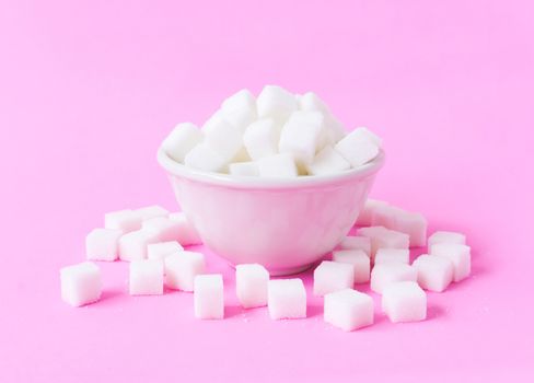 Closeup sugar cubes on bowl with pink background, health care concept
