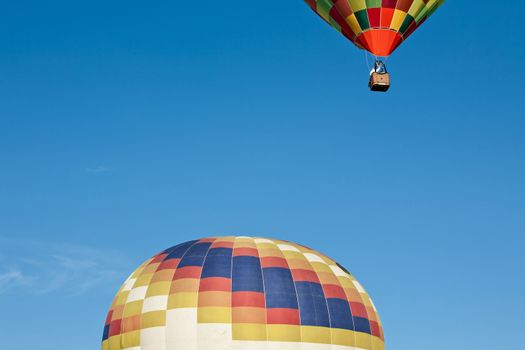 Colorful hot-air balloon ready to get up in flight and another already in flight against a blue sky