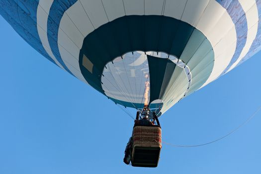 Colorful hot-air balloon is inflated for flight against a blue sky