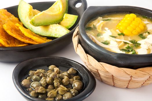 Traditional Colombian ajiaco served with patacon, avocado and capers