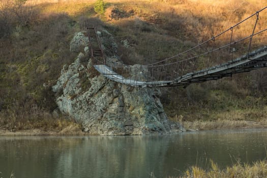 The old hanging footbridge across a small river.