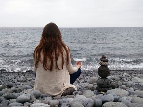 girl meditating in pebble beach in Madeira island, Portugal.