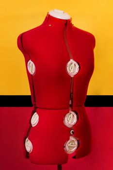 Close view of a red dressmaker dummy over a colorful background.